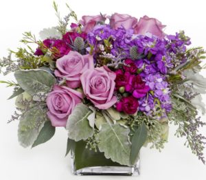 Lavender roses with purple lilacs and greens in vase