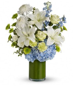 Cool as an ocean breeze, this beautifully serene bouquet features green roses, white lilies, and blue hydrangea in a stunning leaf-wrapped cylinder vase. It's like a vacation for the eyes and they'll adore it.